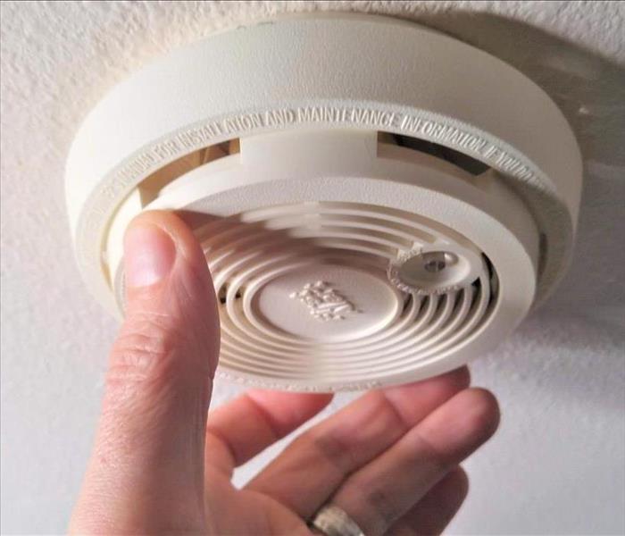 person touching smoke detector on ceiling 